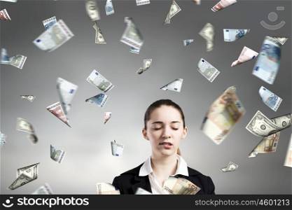 Dreaming to become rich. Young businesswoman standing in the rain of money banknotes