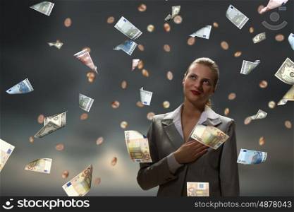 Dreaming to become rich. Young businesswoman standing in the rain of money banknotes