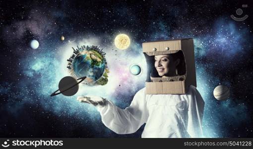 Dreaming to explore space. Young woman with carton box on head imagine she is astronaut. Elements of this image are furnished by NASA