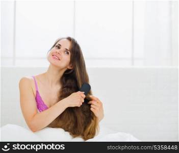 Dreaming woman combing gorgeous long hair