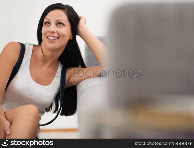 Dreaming young woman sitting on floor near couch