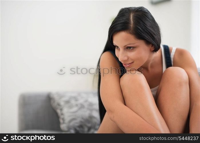 Dreaming young woman sitting on sofa and looking on copy space