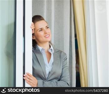 Dreamy business woman near window looking into distance