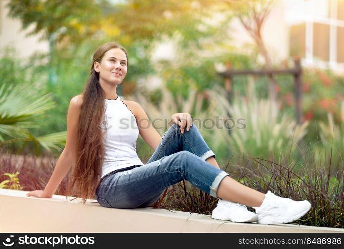 Dreamy girl in the park, nice female sitting in beautiful garden, enjoying freshness of spring nature, with pleasure spending peaceful weekend outside the city. Dreamy girl in the park