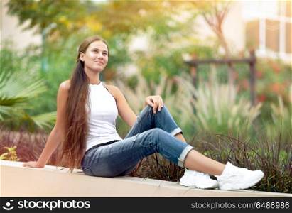 Dreamy girl in the park, nice female sitting in beautiful garden, enjoying freshness of spring nature, with pleasure spending peaceful weekend outside the city. Dreamy girl in the park