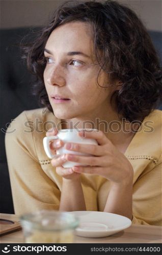 dreamy girl sitting with a cup of coffee in hands