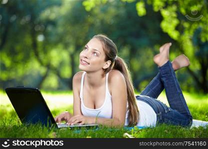 Dreamy girl with a laptop in the park