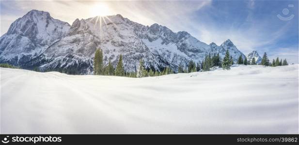 Dreamy winter panorama with the Austrian Alps mountains, the fir forests and a thick layer of snow over a valley, on a sunny day of December.