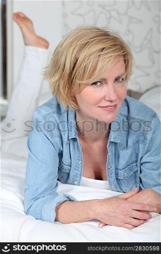 Dressed woman lying on a made bed