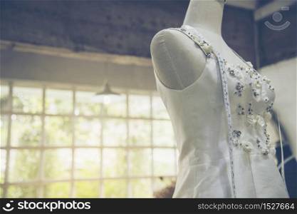 Dressmaker fashion designer make white wedding dresses in mannequins with measure tape for bridal fitting in wedding studio. Fashionable beauty wedding dress style for pretty female. fashion garment