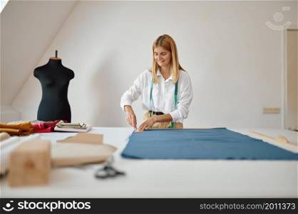 Dressmaker measures cloth at her workplace in workshop. Dressmaking occupation and professional sewing, handmade tailoring business, handicraft hobby. Dressmaker measures cloth at workplace in workshop