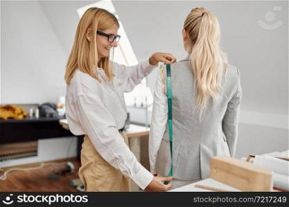 Dressmaker takes measurements from woman in workshop. Dressmaking occupation and professional sewing, handmade tailoring business, handicraft hobby. Dressmaker takes measurements from woman, workshop