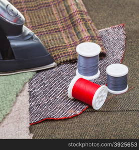 dressmaking still life - clothing iron and thread spools on textile