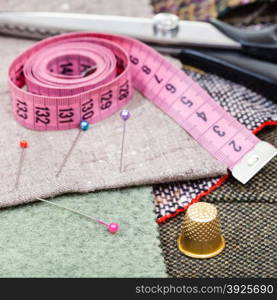 dressmaking still life - pink measuring tape, pins, thimble, shears on tissue