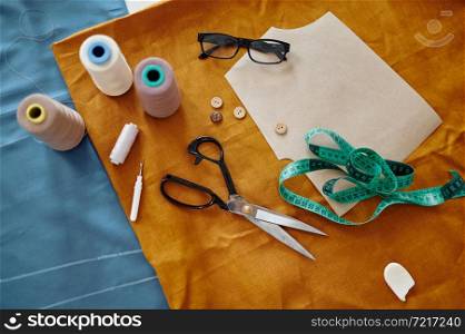 Dressmaking tools on the table, top view, nobody. Professional sewing, handmade tailoring business, handicraft hobby, fabric textile on background. Seamstress or dressmaker accessory. Dressmaking tools on the table, top view, nobody