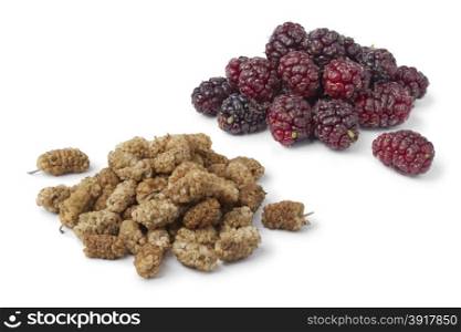 Dried and fresh mulberries on white background