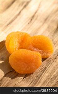 Dried apricots, a healthy snack containing vitamin, beta-carotene, fiber, antioxidants, photographed on wood with natural light (Selective Focus, Focus on the first apricot)