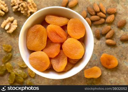 Dried apricots, a healthy snack containing vitamins, beta-carotene, fiber, antioxidants, photographed overhead on slate with natural light (Selective Focus, Focus on the apricots on the top)