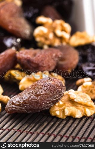 Dried apricots, walnut and plums in a wood background