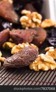 Dried apricots, walnut and plums in a wood background