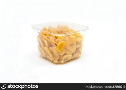 Dried Banana Chips. Sliced and dried bananas in a clear airtight plastic container on a white background