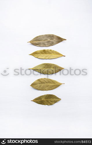 Dried bay leaves isolated on white wooden background with copy space.