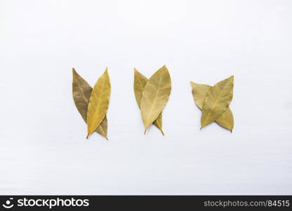 Dried bay leaves on white wooden background.