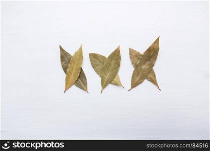 Dried bay leaves on white wooden background.
