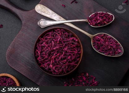 Dried beets in small slices in a wooden bowl on a black concrete background. Asian cuisine