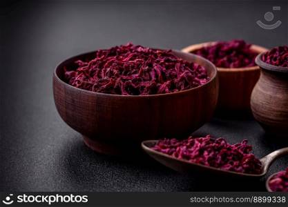 Dried beets in small slices in a wooden bowl on a black concrete background. Asian cuisine