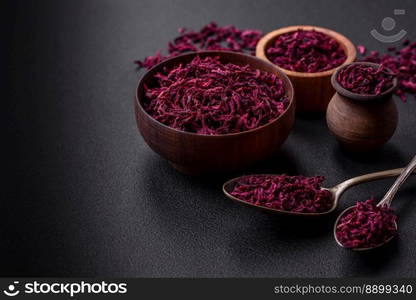 Dried beets in small slices in a wooden bowl on a black concrete background. Asian cuisine