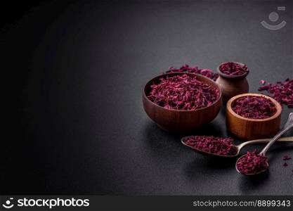 Dried beets in small slices in a wooden bowl on a black concrete background. Asian cuisine