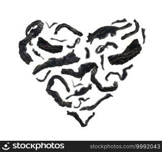 Dried black tea close up in the shape of a heart on white background.. Dried black tea close up in the shape of a heart on white background