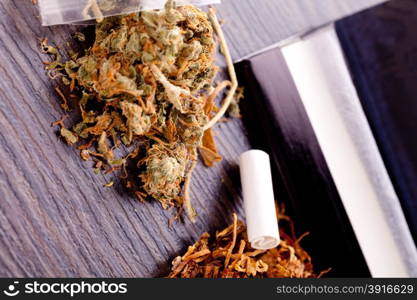 Dried Cannabis on Rolling Paper with Filter. Close up Dried Cannabis Leaves on a Resealable Cellophane Wrapper and a Rolling Paper with Filter on Top of the Table