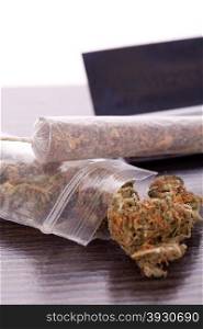 Dried Cannabis on Rolling Paper with Filter. Close up Dried Cannabis Leaves on a Resealable Cellophane Wrapper and a Rolling Paper with Filter on Top of the Table