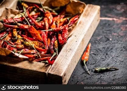 Dried chili peppers in a wooden tray. Against a dark background. High quality photo. Dried chili peppers in a wooden tray.