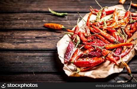 Dried chili peppers on paper. On a wooden background. High quality photo. Dried chili peppers on paper.