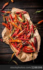 Dried chili peppers on paper. On a wooden background. High quality photo. Dried chili peppers on paper.