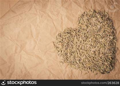 Dried fennel dill seeds heart shaped on paper surface with copy space. Fennel dill seeds heart shaped on paper surface