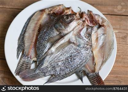 dried fish on white plate, tilapia fish for cooking food on wooden - food preservation dry fish