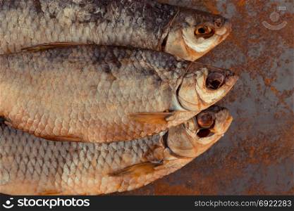 Dried fish. Salty dry river fish on a rusty metal plate background.