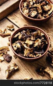 Dried forest mushrooms in a plate on the rustic wooden table. Sliced dried mushrooms,wooden table
