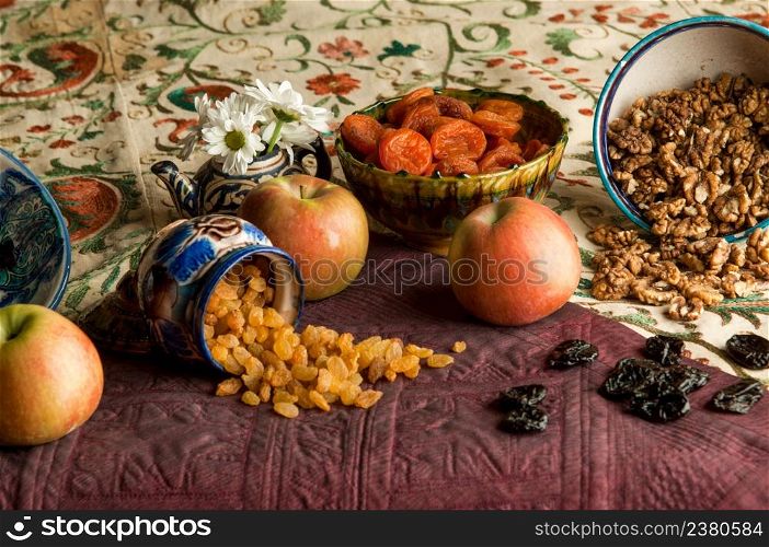 dried fruit in cups on an oriental ornamented tablecloth. still life in oriental style. oriental fruit