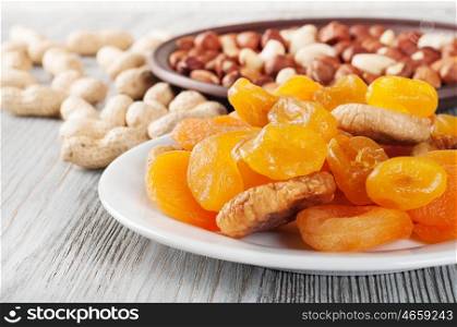 Dried fruits and nuts on a wooden background. Candied fruits, lemon, apricot, fig and nuts in plate.