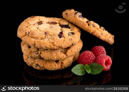 Dried fruits chip cookies and raspberries isolated on black background.