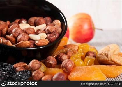 Dried fruits, lemon, apricot, fig and nuts in black plate on a wooden background.