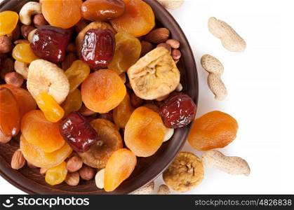 Dried fruits on a white background. Dates, lemon, apricots, figs and nuts in a clay plate. Top view.