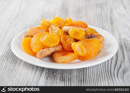 Dried fruits on a wooden background. Candied fruits, lemon, apricot, figs. Fruits in white plate.