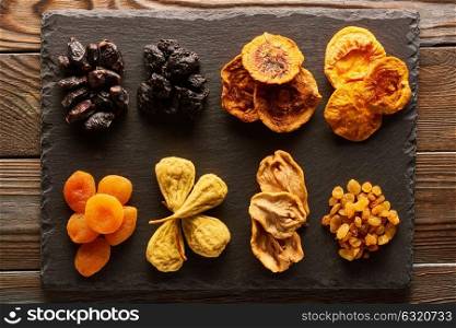 Dried fruits on slate plate over vintage rustic wooden background