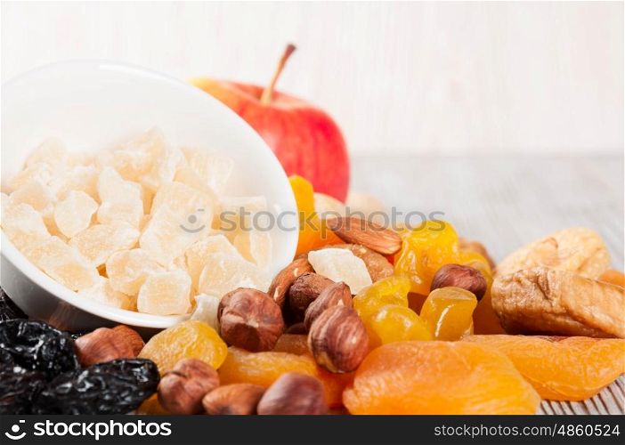 Dried fruits, red ripe apple and nuts on a wooden background